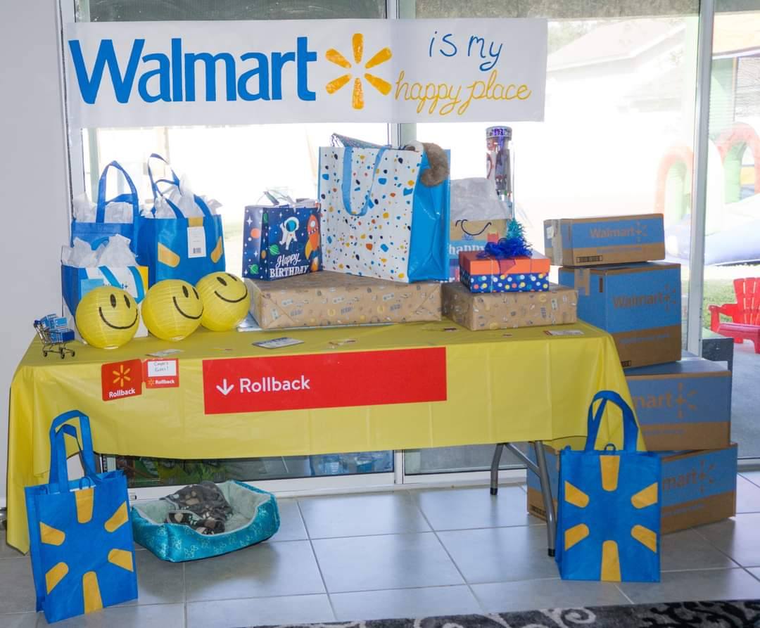 Decorated table featuring Walmart-themed birthday gifts, shopping bags, and Rollback signage.