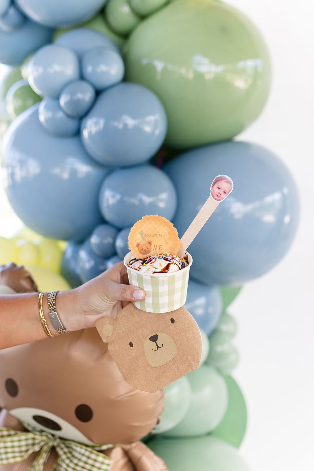 Cup of ice cream decorated for a first birthday party with a bear-themed wafer and stick topper.