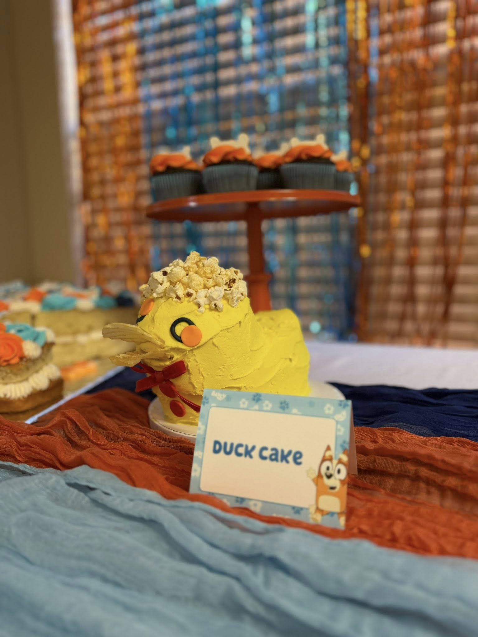 Yellow duck cake topped with popcorn sitting on a table with a Duck Cake label.