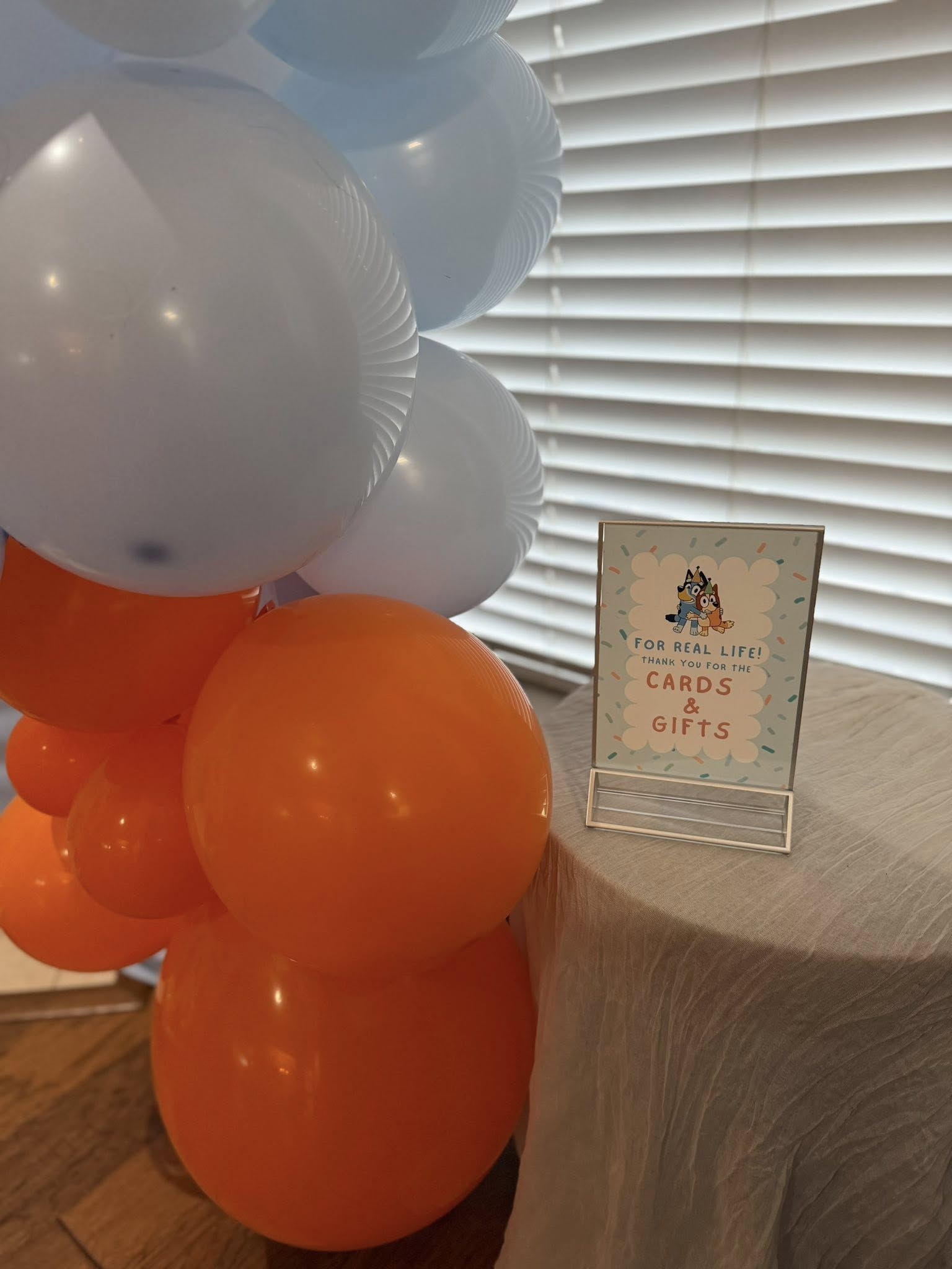 Bluey-themed cards and gifts table sign with orange and light blue balloons