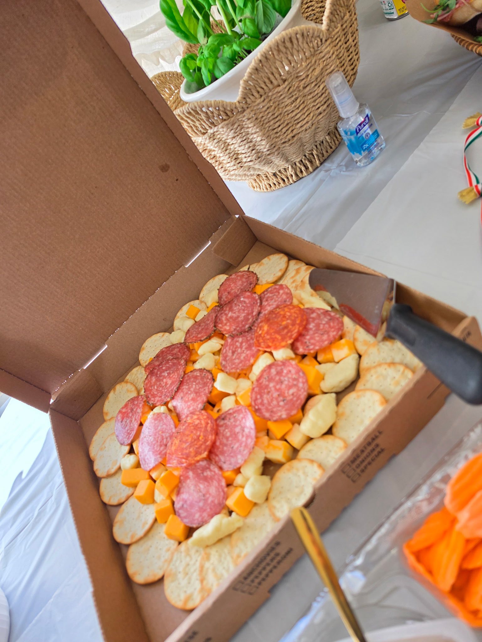Charcuterie pizza box filled with round crackers, cubed cheddar cheese, and slices of salami and pepperoni.