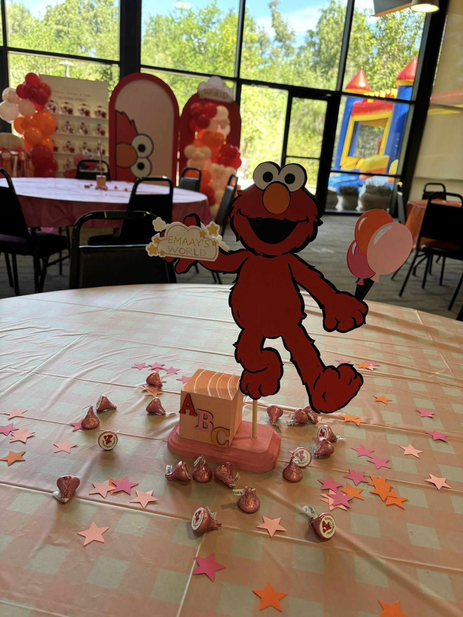 Elmo themed centerpiece on a decorated party table with paper stars and chocolate kisses.