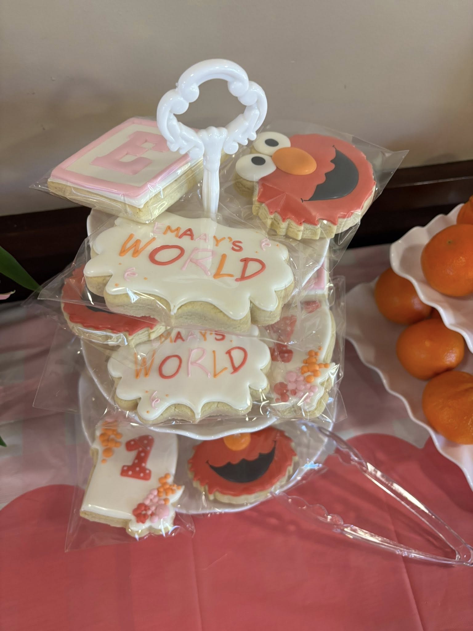 Tiered tray filled with individually wrapped sugar cookies featuring Elmo designs and text reading Emaay's World.
