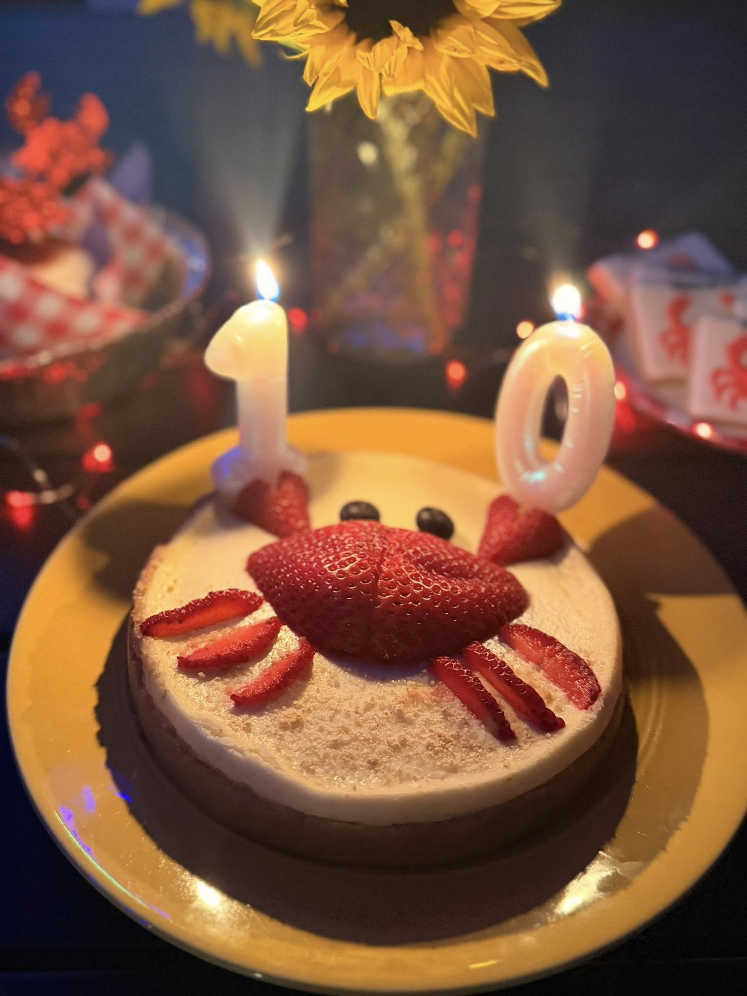 Cheesecake decorated with a strawberry crab design and number 10 candles for a 10th birthday celebration.