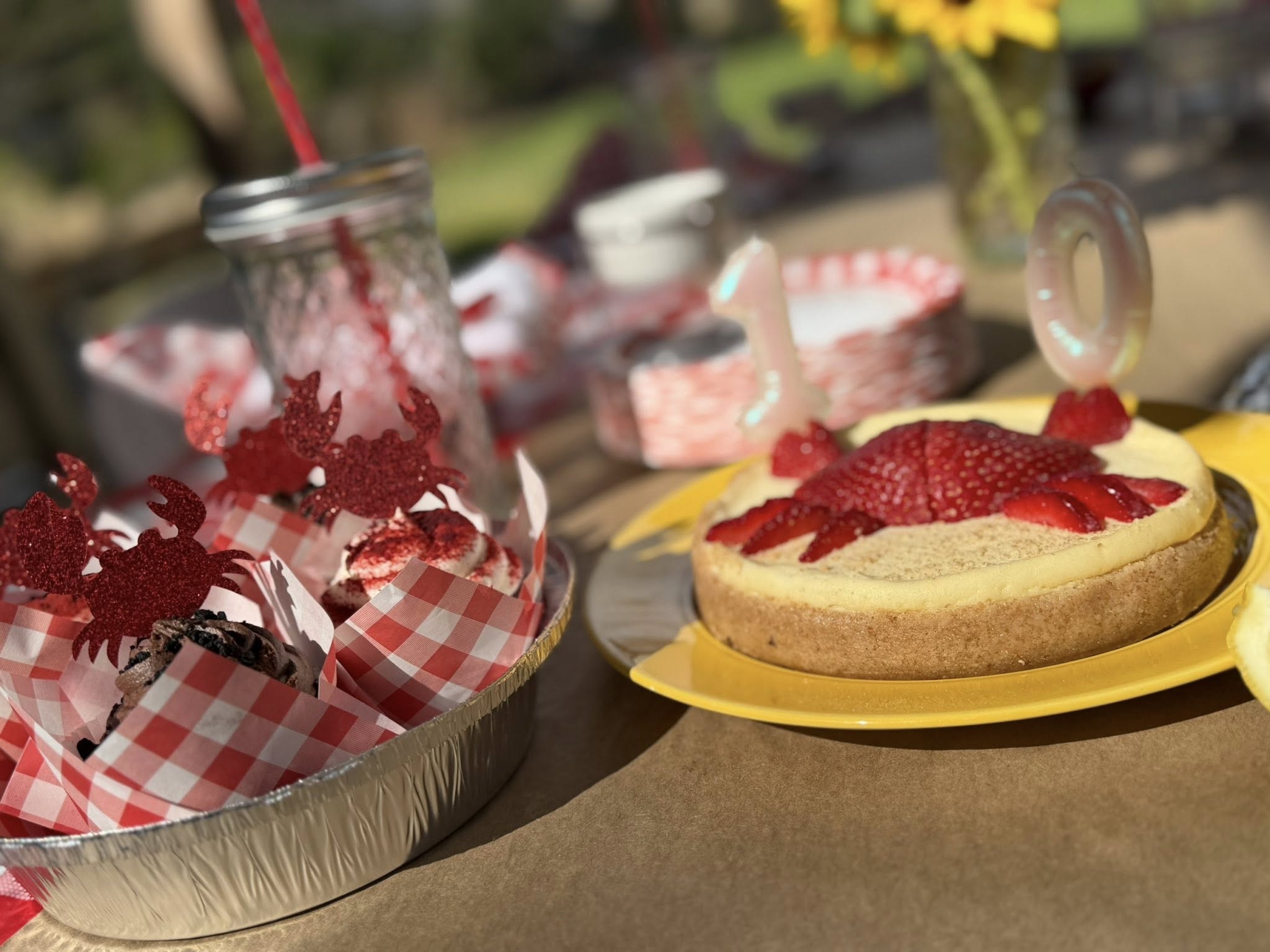 Crab-themed birthday desserts with a strawberry crab cheesecake and cupcakes decorated with red glitter crabs.