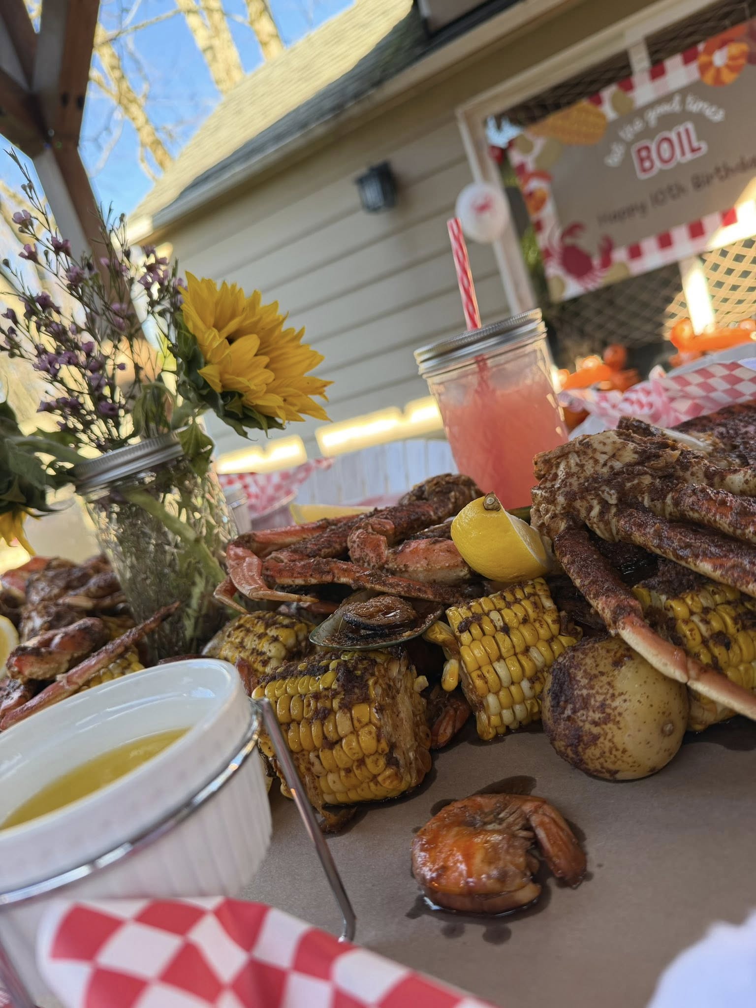 Table spread showcasing a seafood boil with crab legs, corn, potatoes, shrimp, lemon wedges, and drawn butter