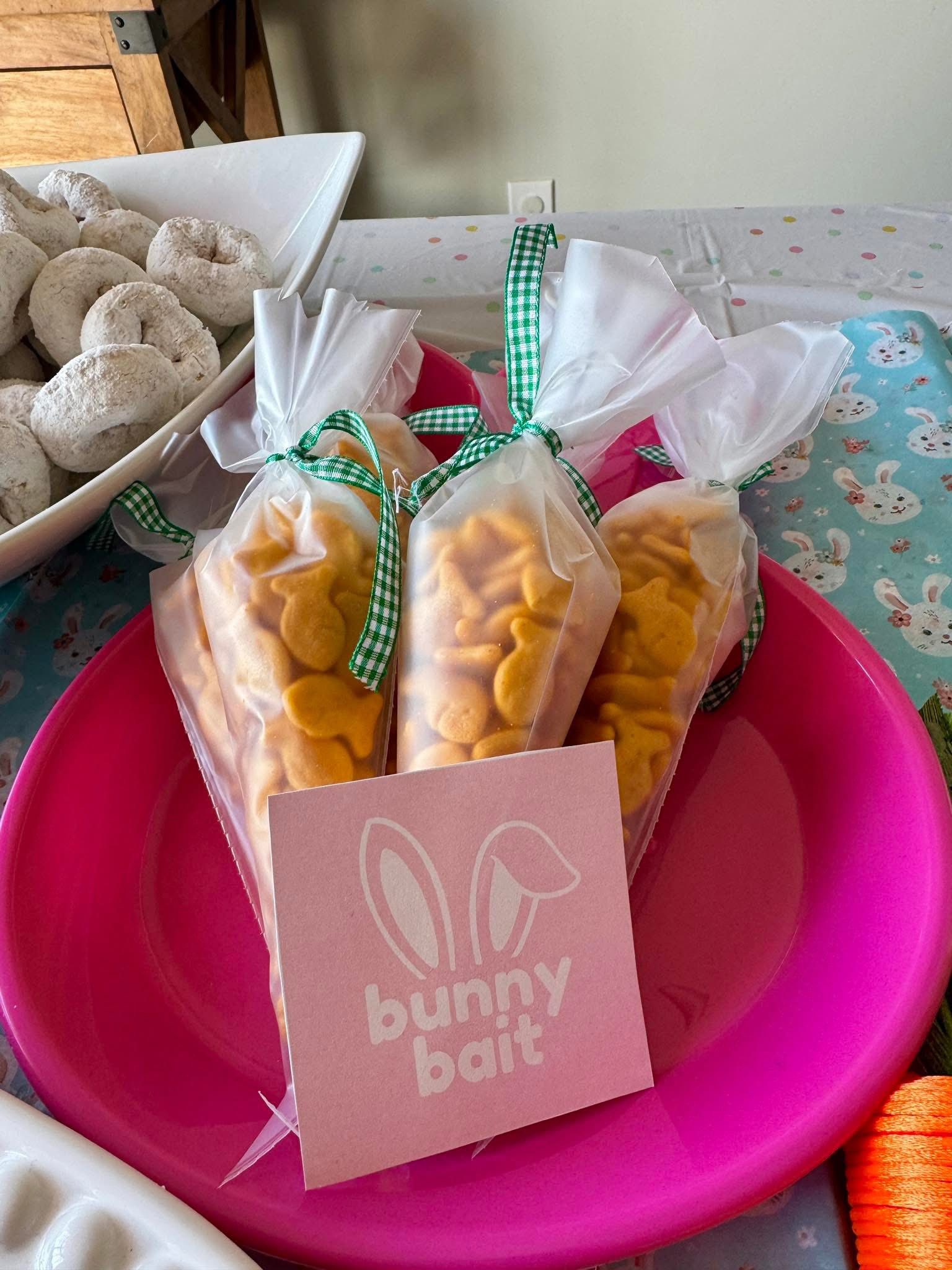 Three cone-shaped bags of fish-shaped crackers tied with green gingham ribbon featuring a pink Bunny Bait tag.