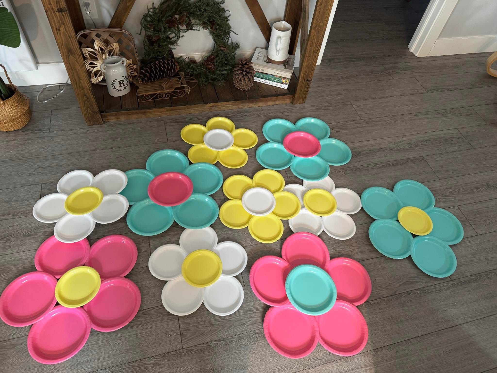 Colorful paper plates arranged in flower shapes on a wooden floor