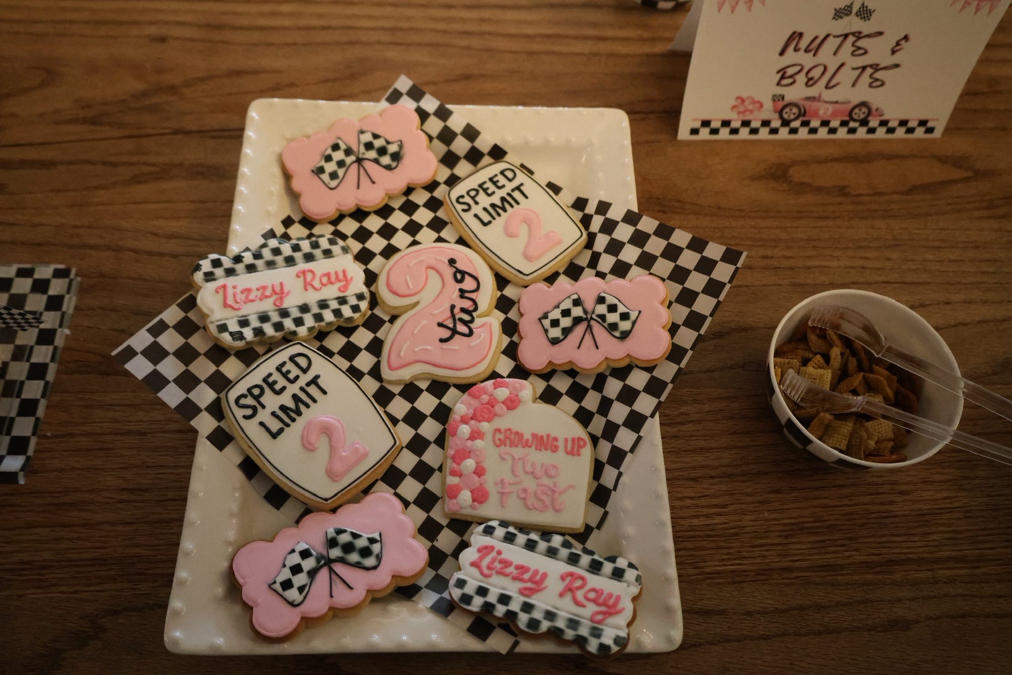 Racing-themed second birthday cookies with checkered patterns and Lizzy Ray frosting on a white serving platter.