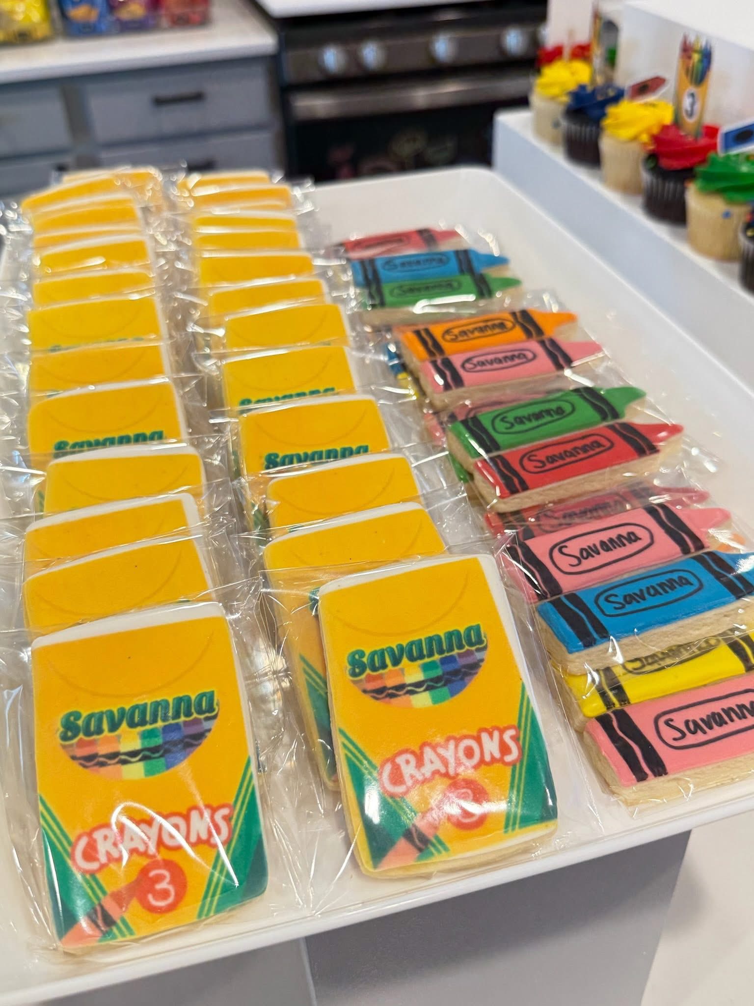 Custom crayon-shaped and crayon box cookies personalized with the name Savanna for a third birthday party.