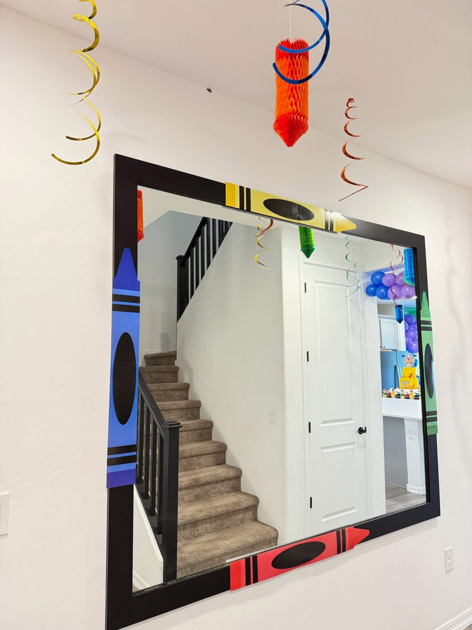 Wall mirror decorated with colorful crayon-shaped accents for a party