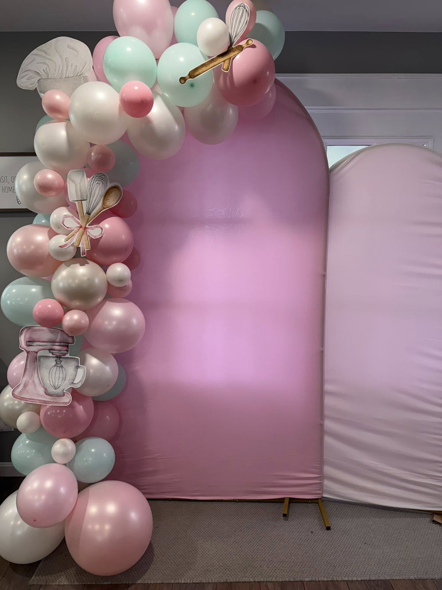 Baking-themed balloon garland with pink, mint, and white balloons decorated with chef hat, mixer, and spoon cutouts