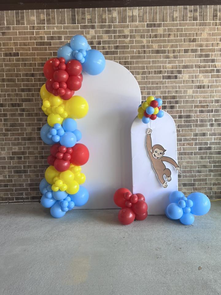 Curious George themed balloon arch and double white backdrop display for a birthday party