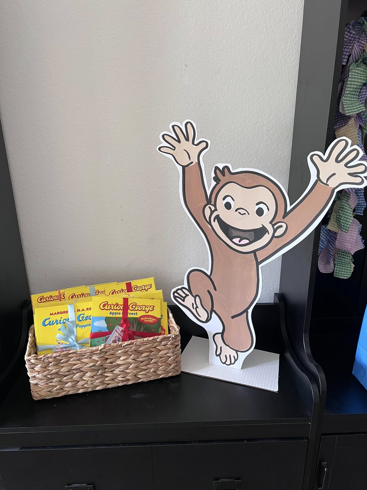 Basket filled with Curious George books next to a Curious George cutout display