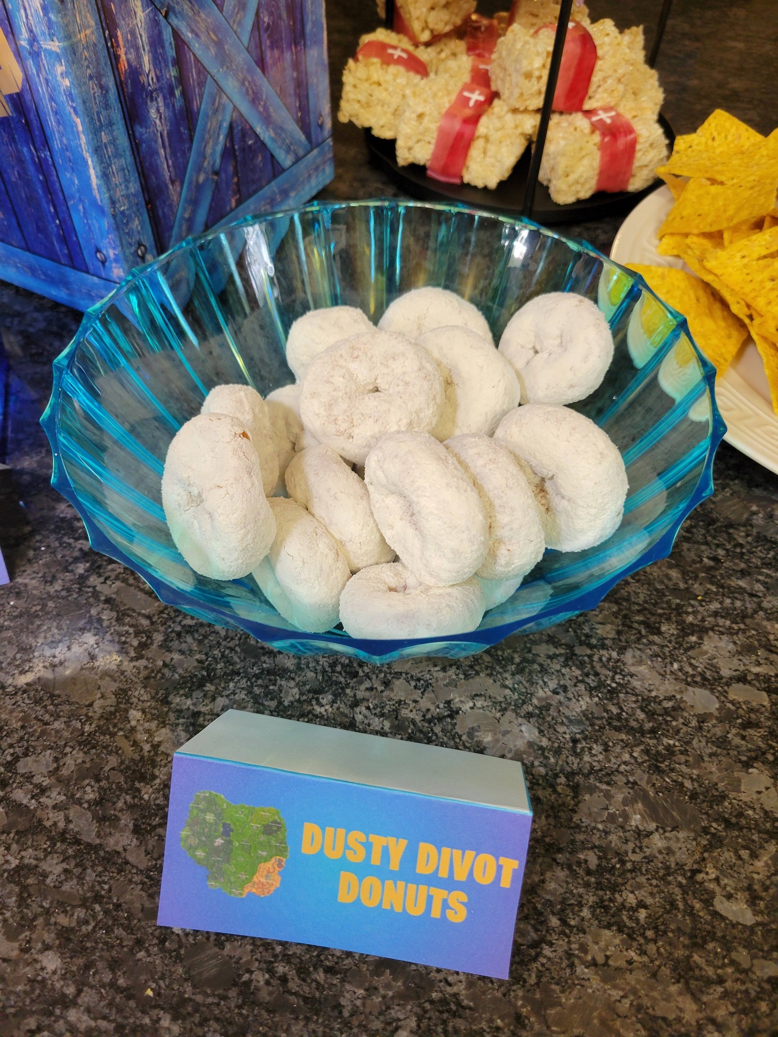 Bowl of powdered mini donuts with a sign labeled Dusty Divot Donuts.