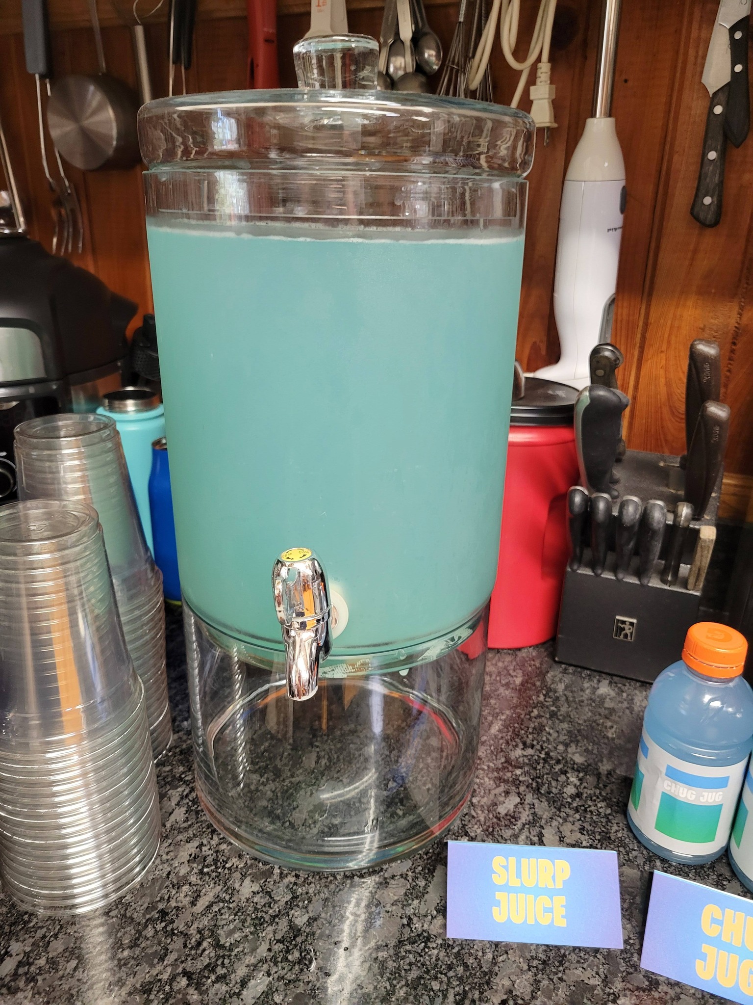 Glass beverage dispenser filled with blue Slurp Juice for a party