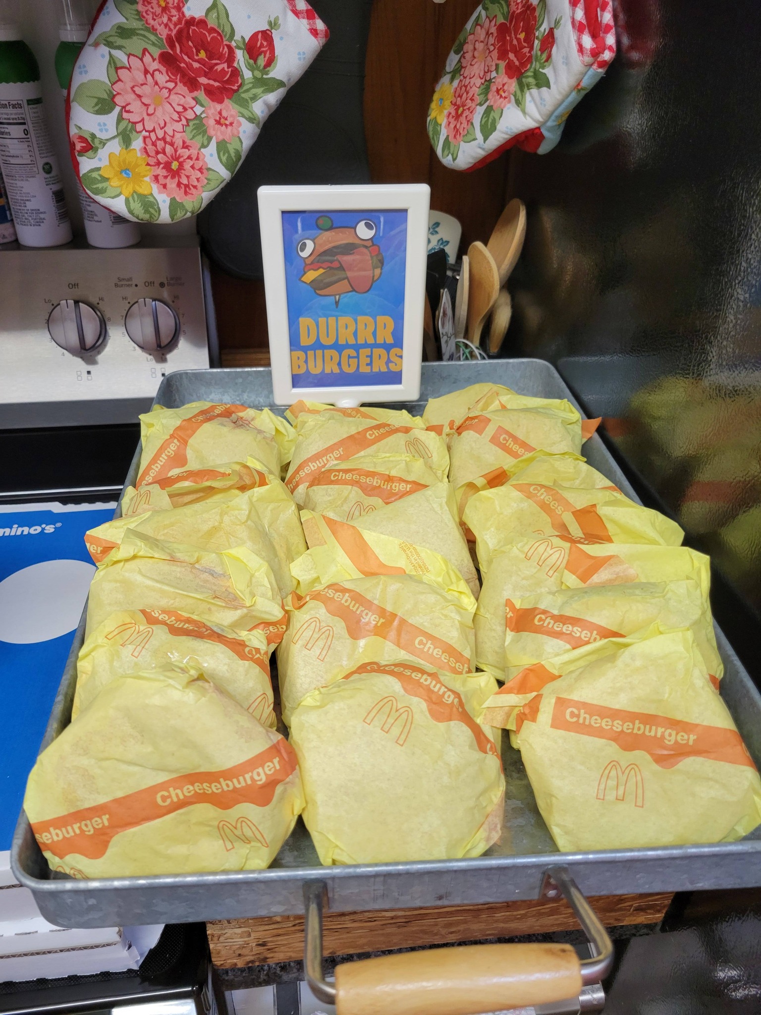 Tray of wrapped McDonald's cheeseburgers with a decorative Durrr Burger sign behind them.