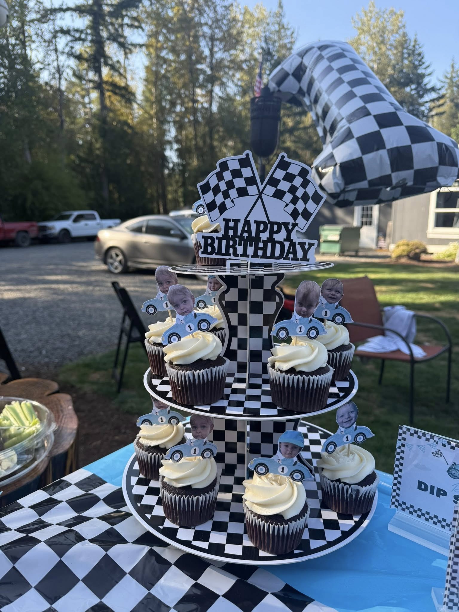 Cupcake tier stand decorated with racing theme and custom photo toppers for a first birthday party.