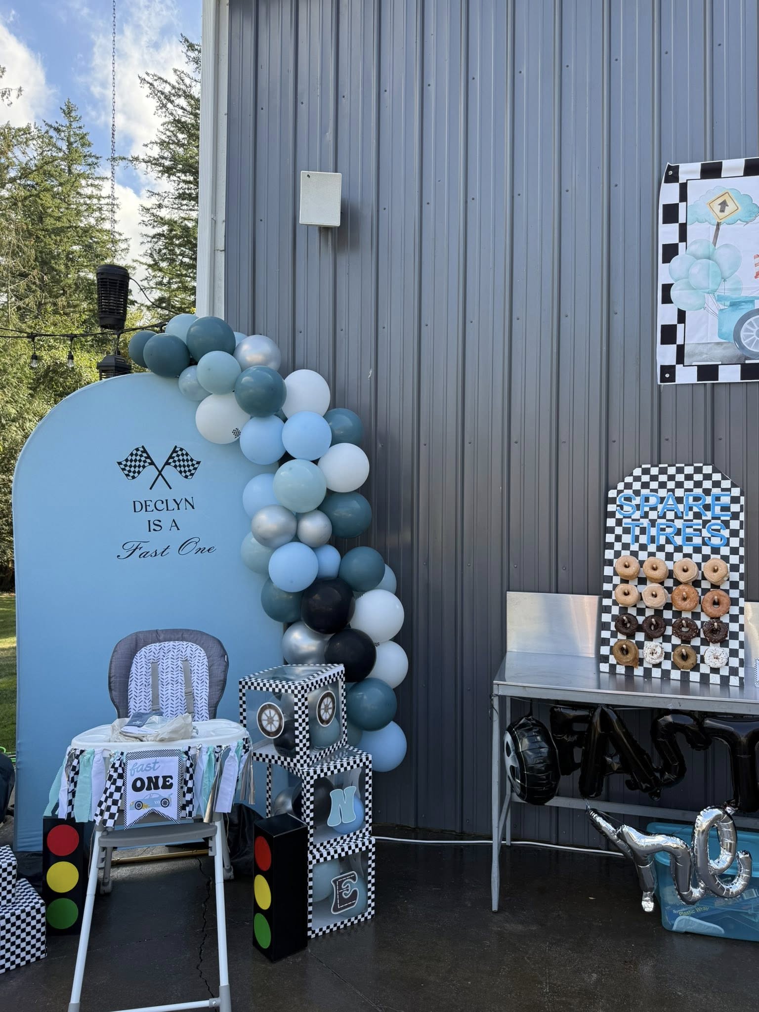 Race car-themed first birthday party decorations, including a balloon arch, donut wall, and high chair setup.