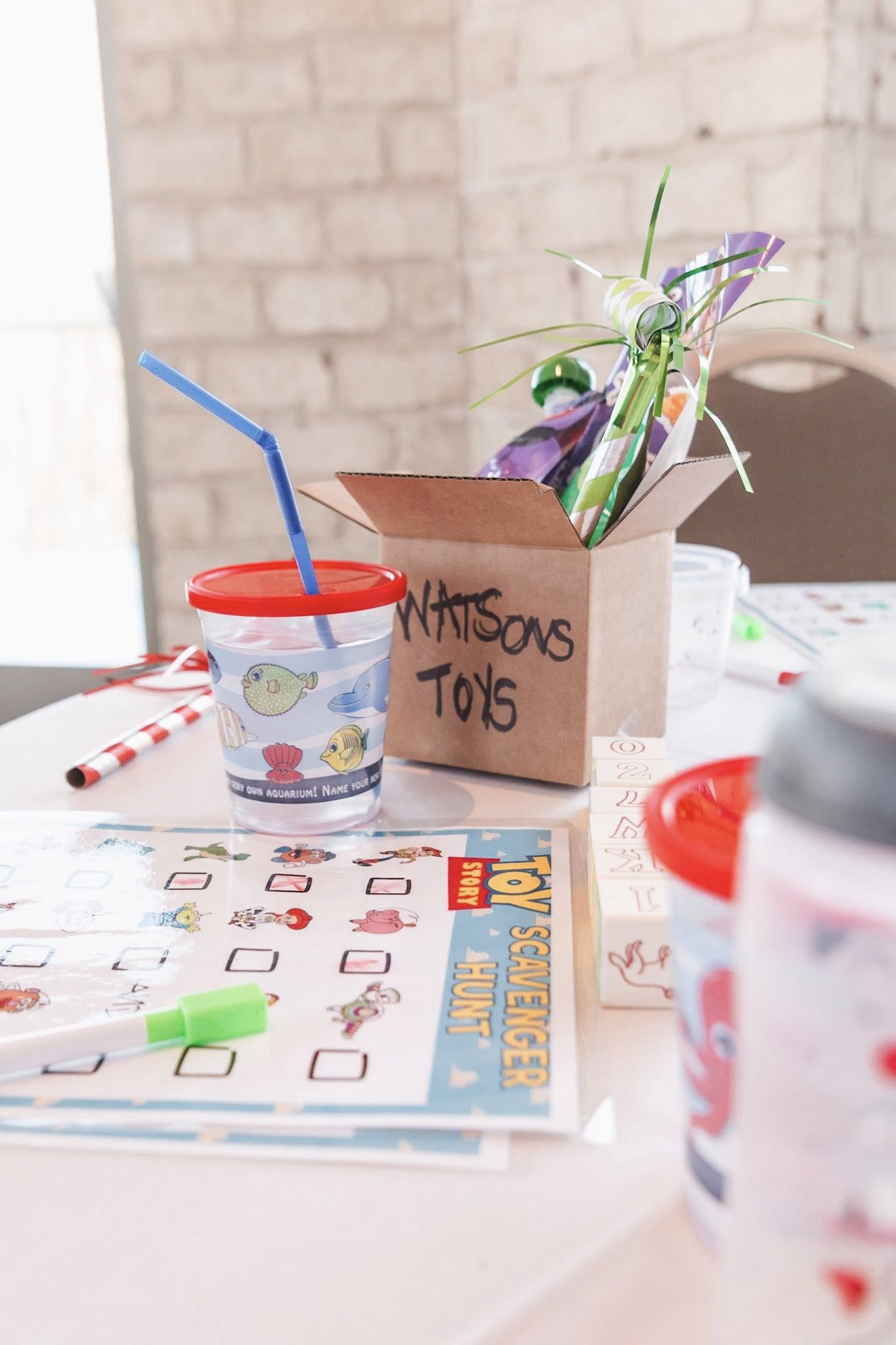 Toy Story scavenger hunt sheet and party supplies with a box labeled Watsons Toys on a table.