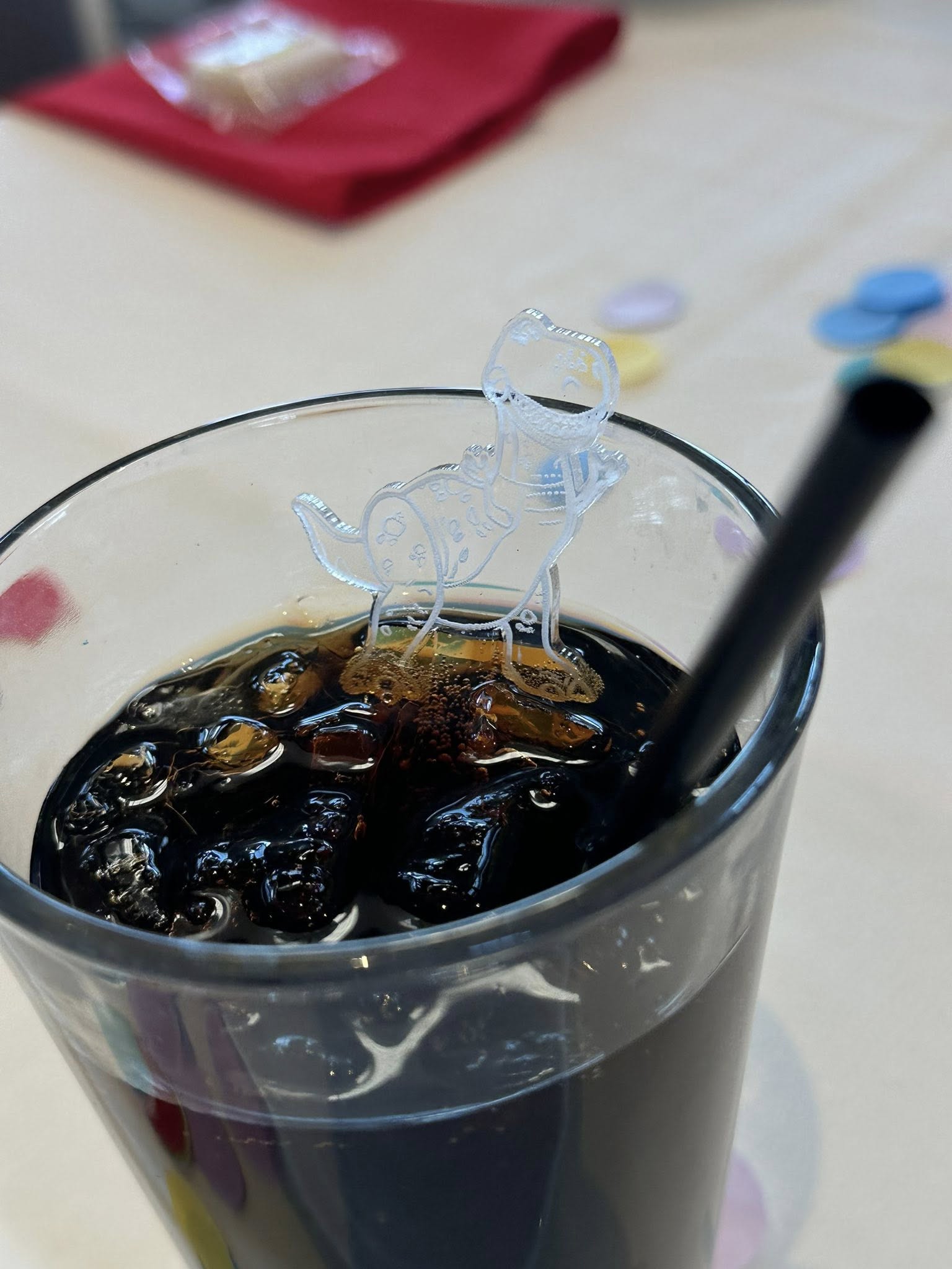 Glass of iced coffee with a clear decorative dinosaur drink stirrer.