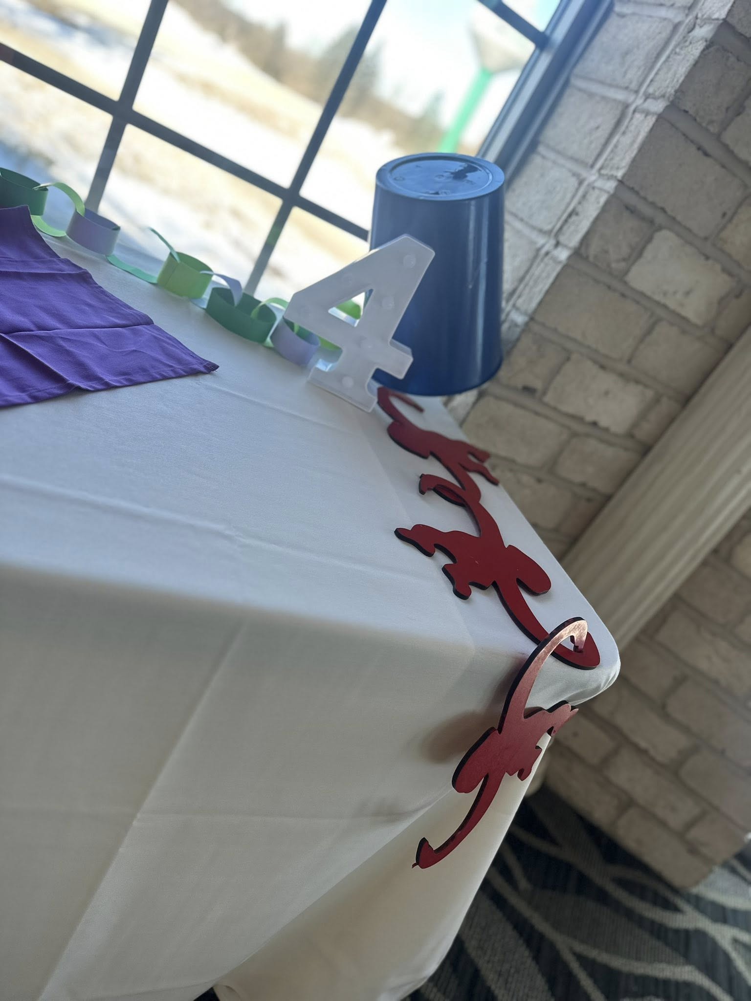 Birthday party table decorated with a number four sign, red gecko garland, and paper chain.