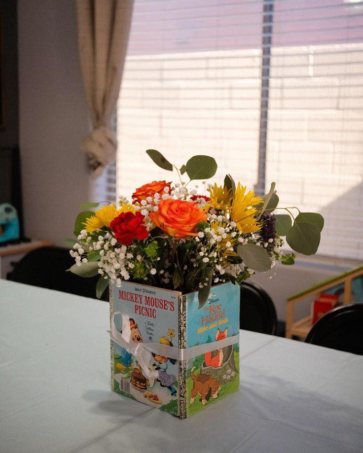 Table flower arrangement in a vase made from vintage Disney books