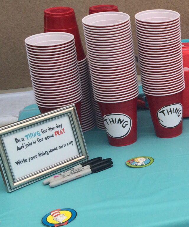 Stacks of red party cups labeled Thing next to a sign inviting guests to write their name on a cup.