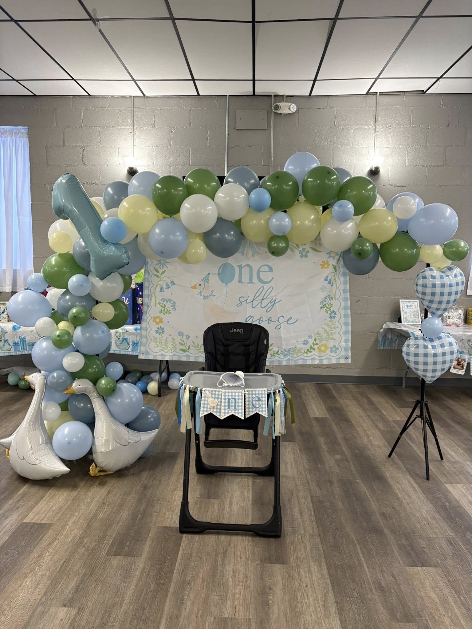 One Silly Goose themed first birthday party decor with balloon arch, goose balloons, and high chair.