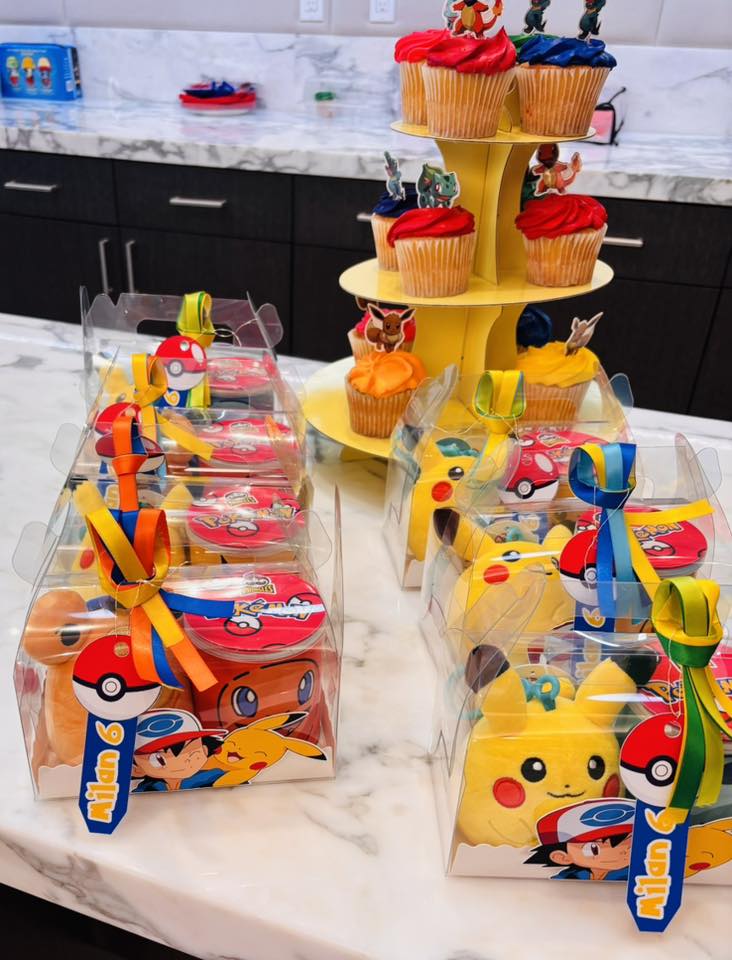 Pokemon themed birthday party treat boxes with Pikachu, Poke Balls, and matching cupcakes on a yellow tiered stand