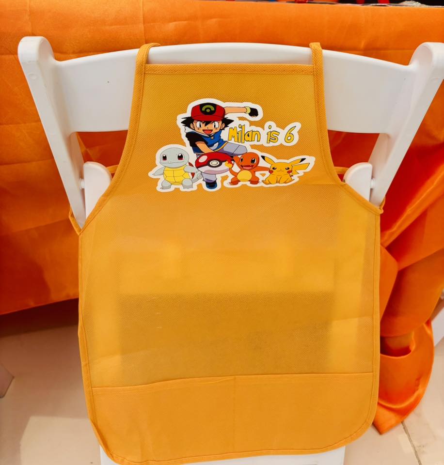 Personalized yellow kids apron featuring Ash, Pikachu, and other Pokemon characters with the text Milan is 6