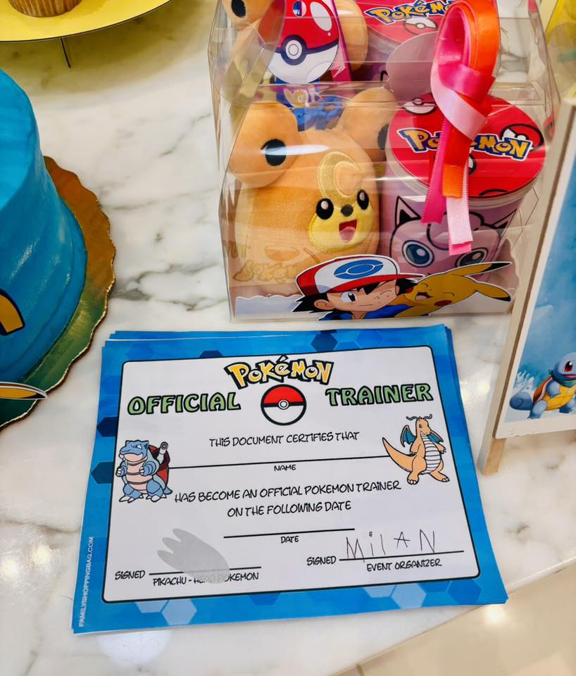 Official Pokemon Trainer certificate next to a clear gift box containing Pokemon plush toys and party favors.