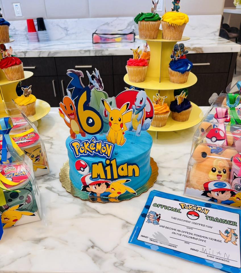 Blue Pokemon themed birthday cake for Milan's 6th birthday surrounded by Pokemon cupcakes and trainer certificate