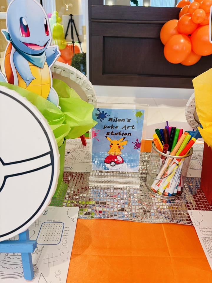 Pokemon-themed art station with a sign for Milan's Poke Art Station, markers, and coloring sheets.