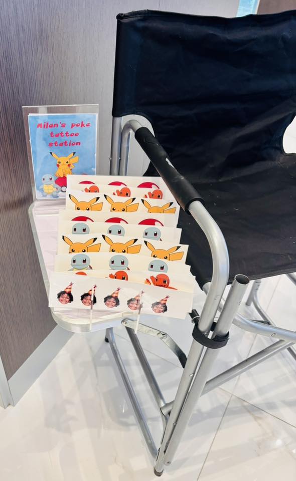 Temporary Pokemon-themed tattoo station featuring illustrated designs and a sign for Milan's Poke Tattoo Station.