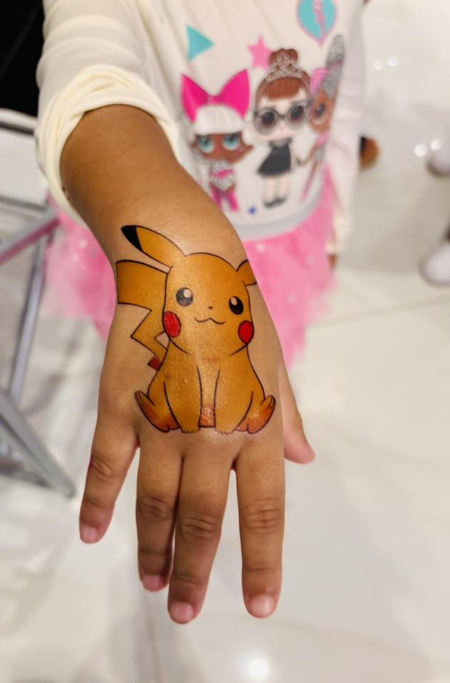 Child's hand featuring a temporary tattoo of Pikachu from Pokemon.