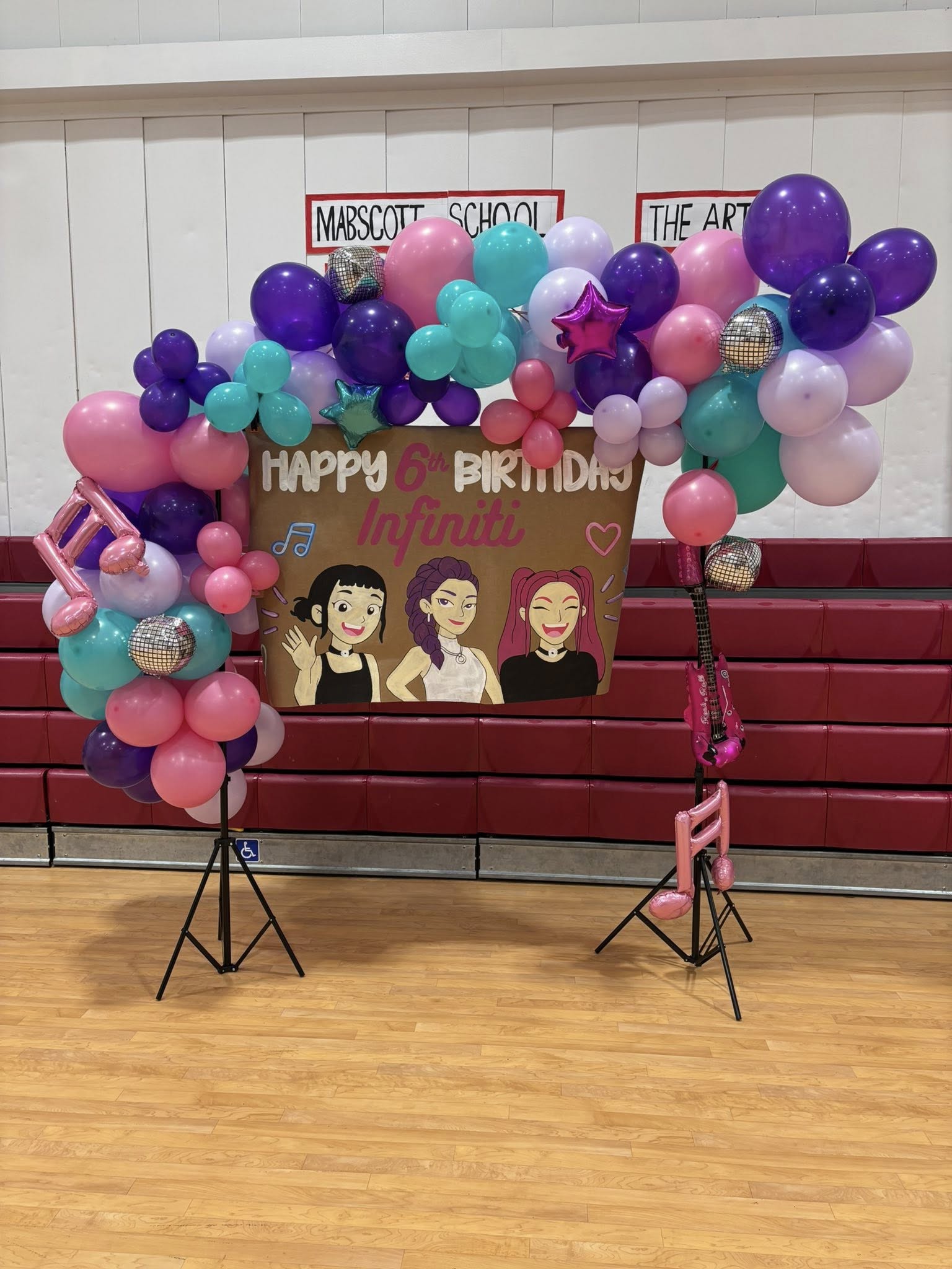 Rockstar-themed balloon arch backdrop with a sign saying Happy 6th Birthday Infiniti.