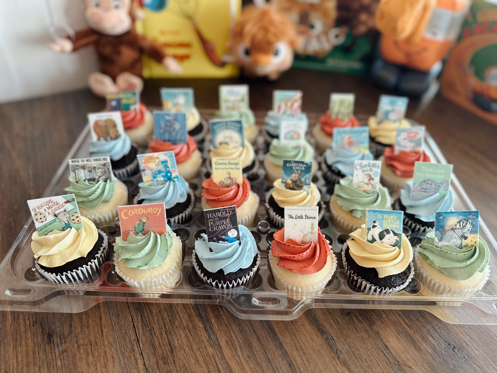 Collection of cupcakes decorated with miniature book cover toppers from classic children's stories.