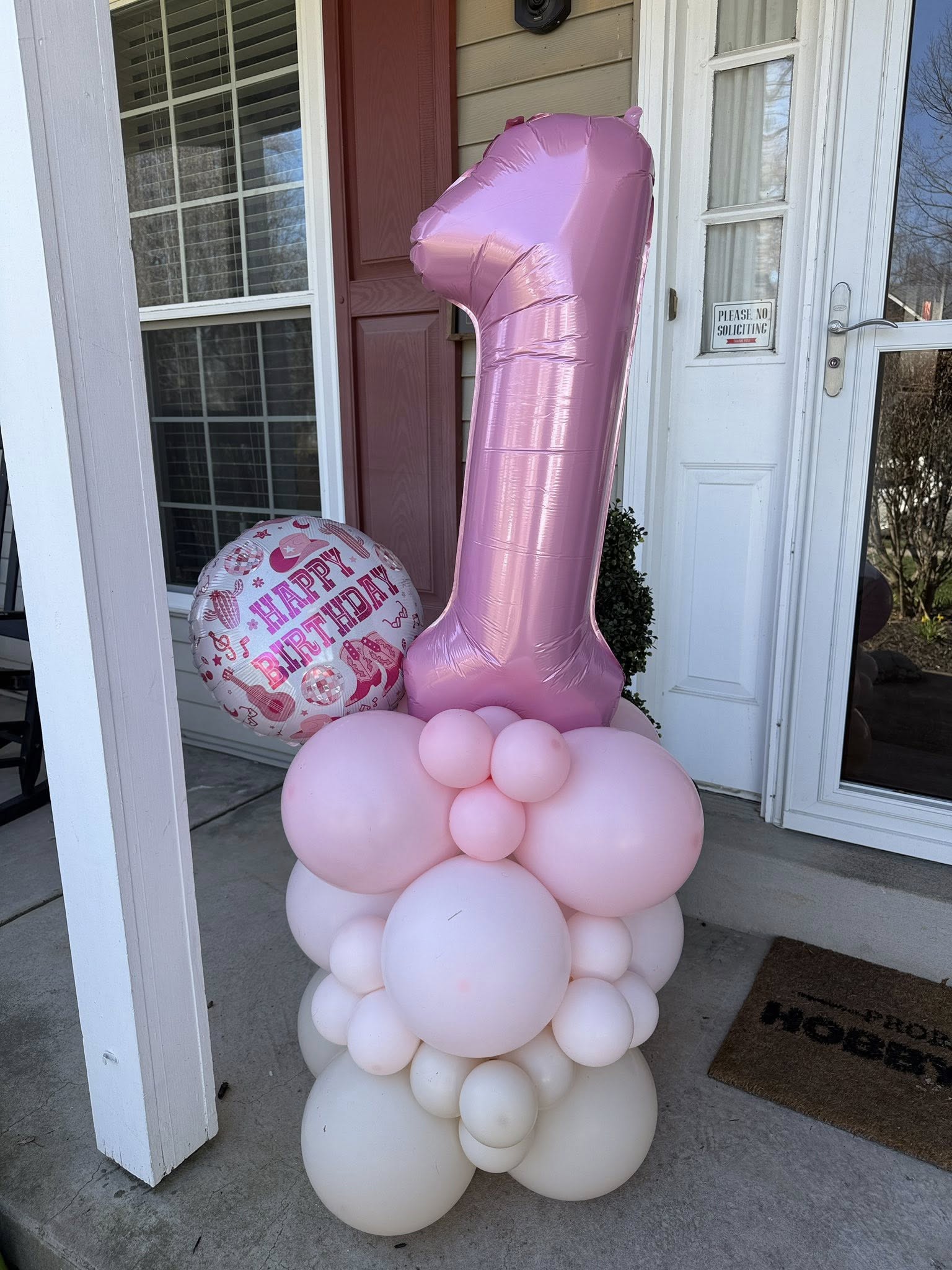 First birthday balloon decoration with a large pink number one foil balloon and Happy Birthday western themed accents