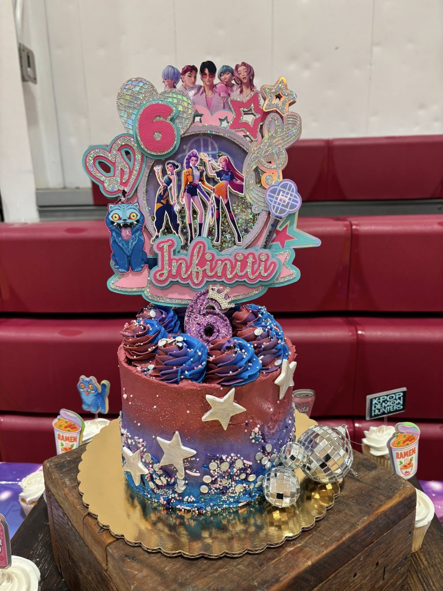Custom K-Pop theme birthday cake with blue and red ombre frosting, star sprinkles, edible disco balls, and a personalized Infiniti cake topper.