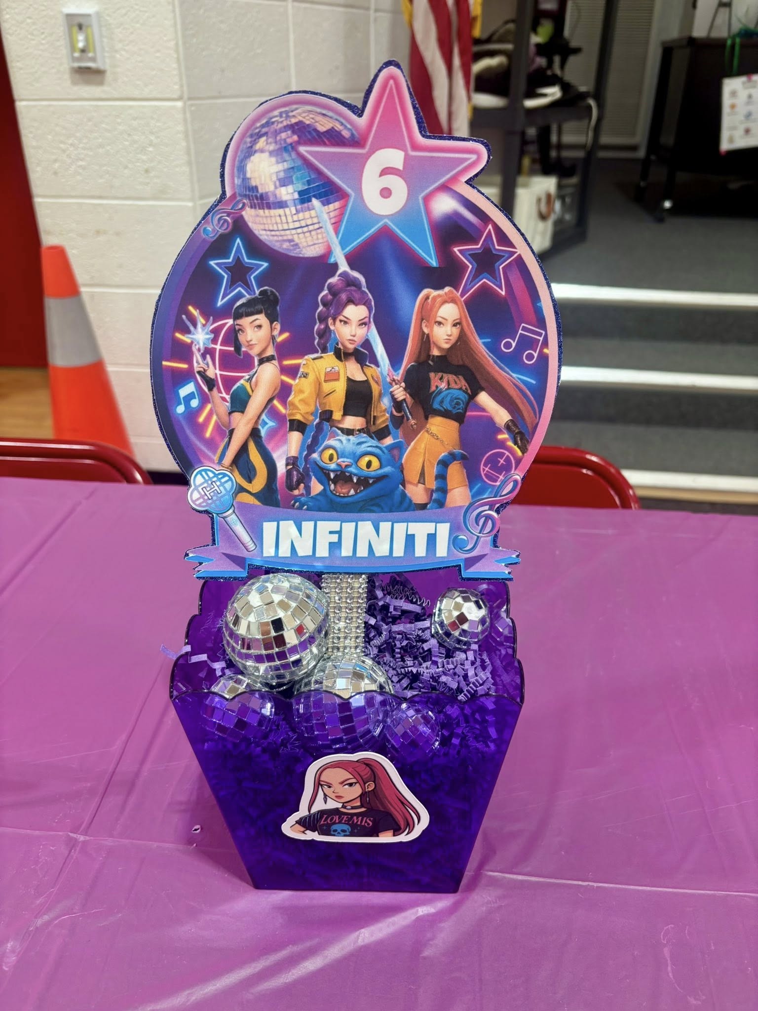 Custom K-pop themed party centerpiece featuring a pop-star cutout with the name Infiniti and a birthday age of 6.