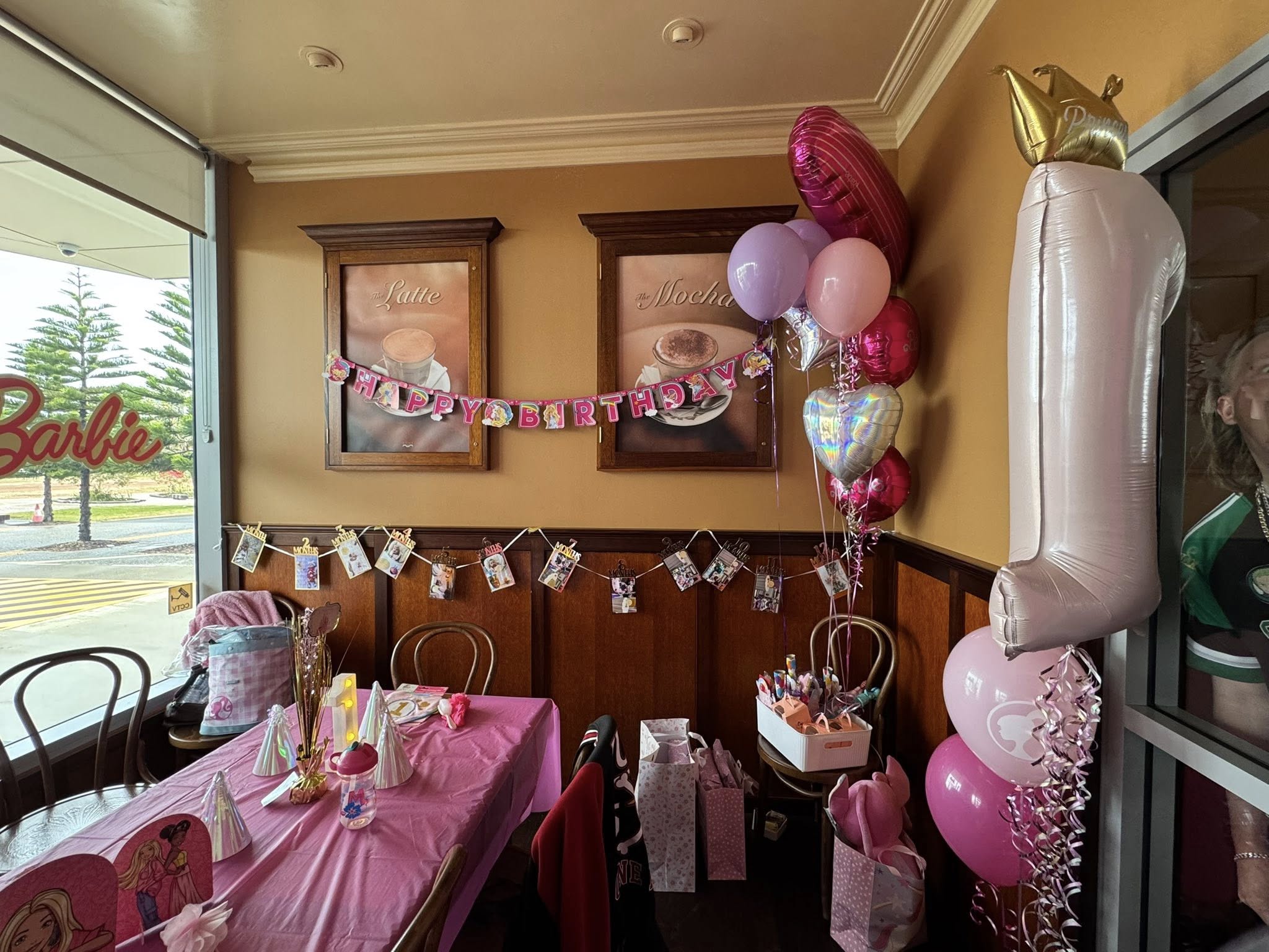 Birthday party table set up with pink decorations and a number one balloon.