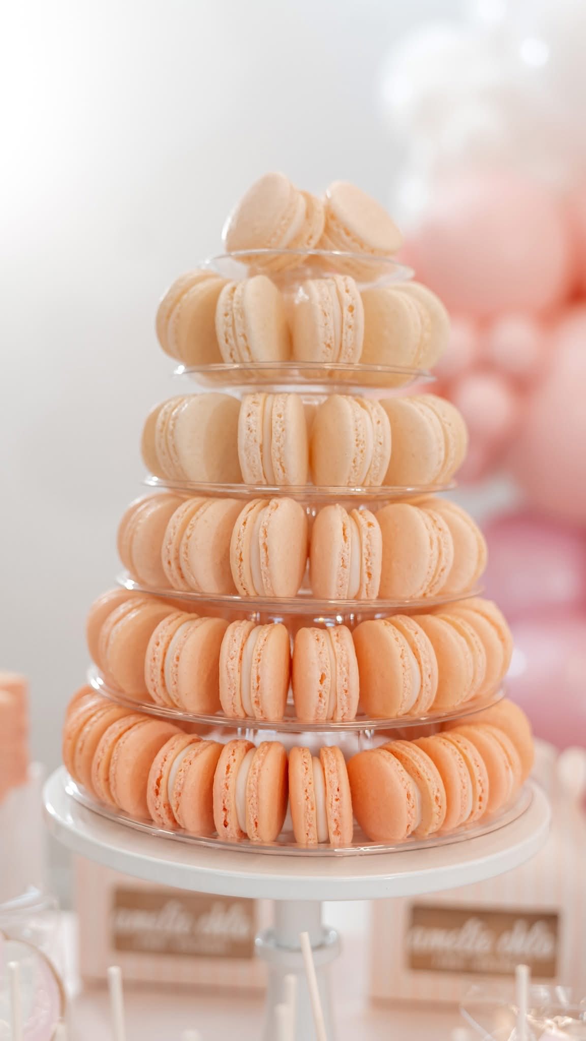Tiered stand filled with peach-colored macarons at a party