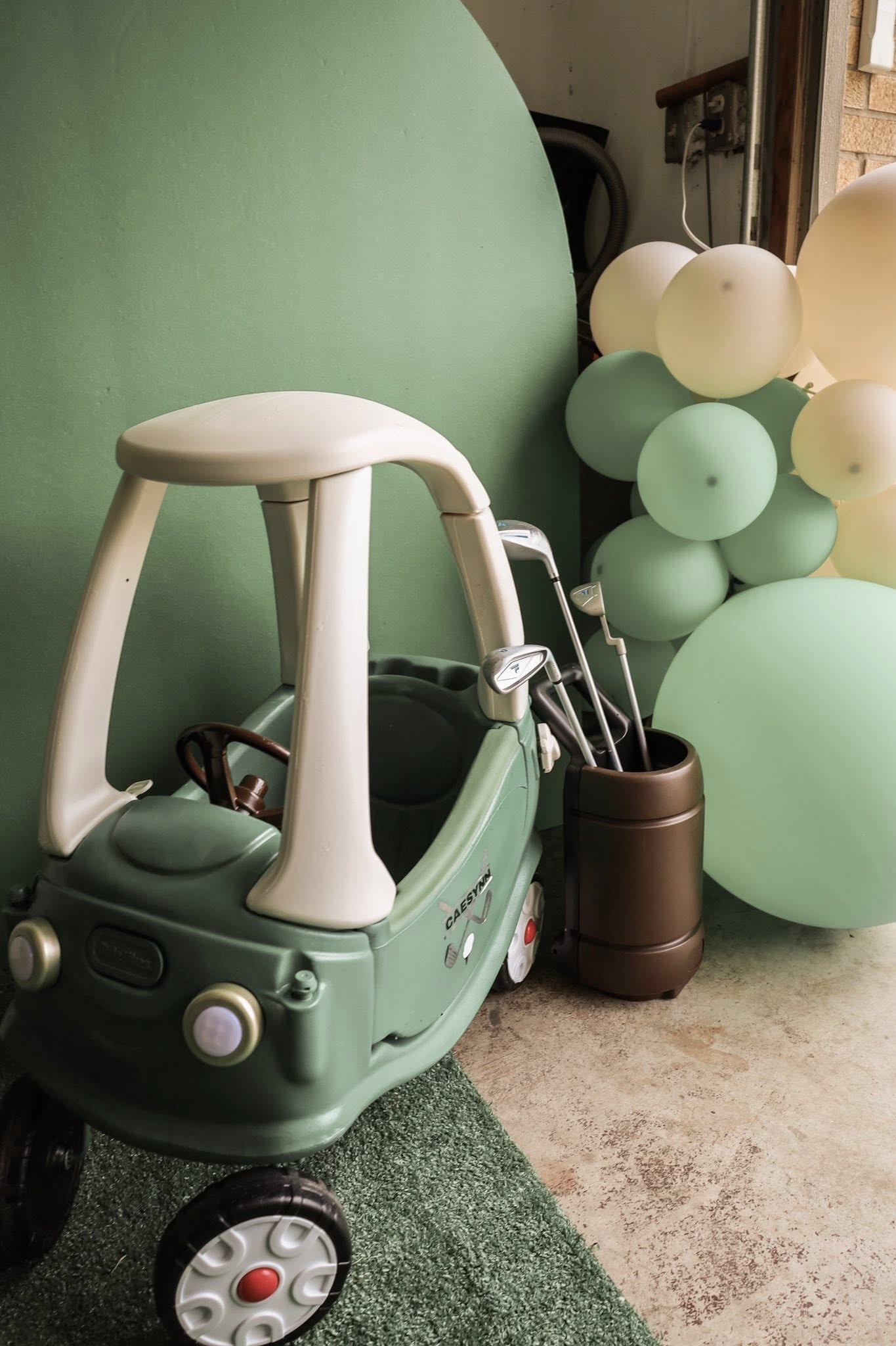Personalized green toy car with golf clubs in a stand next to pastel party balloons