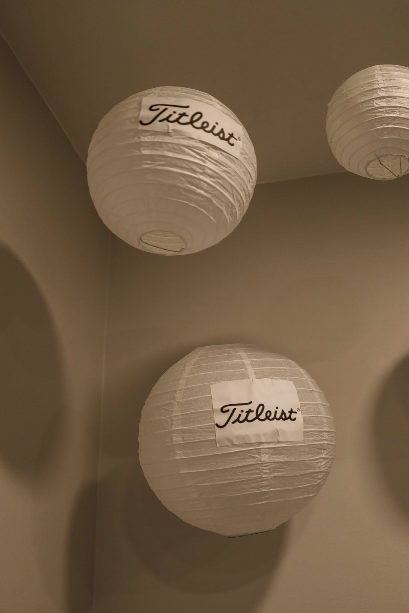 White round paper lanterns hanging with Titleist logo labels attached