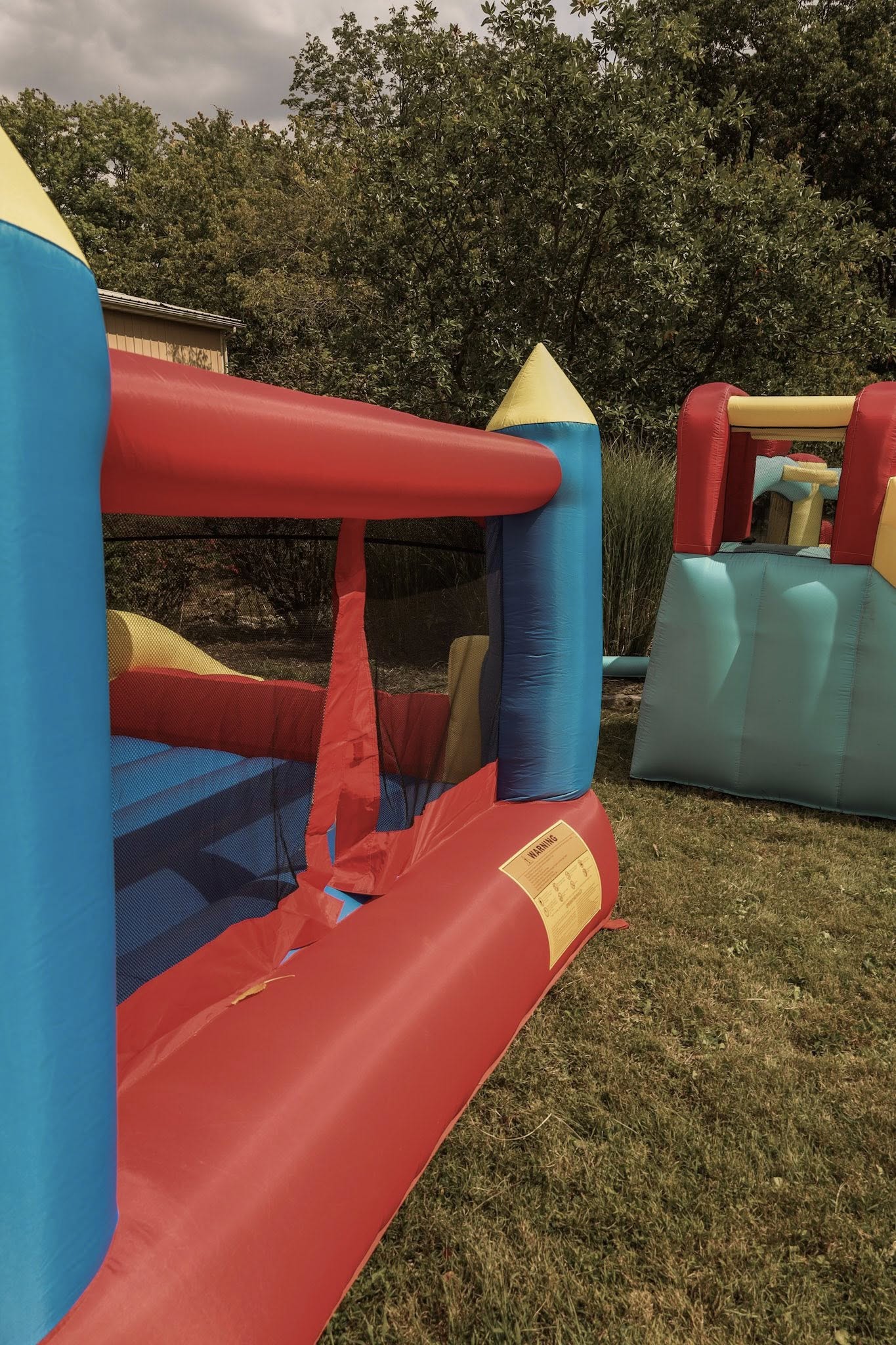 Colorful inflatable bounce house with safety warning label on a grassy lawn.