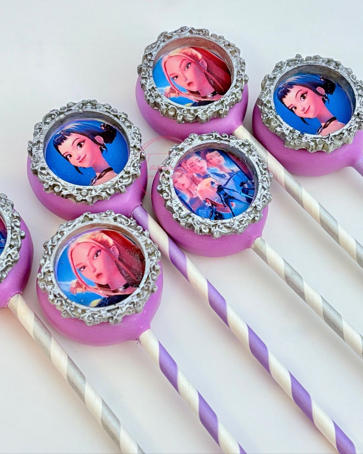 Custom lilac cake pops decorated with silver ornate frames featuring printed character edible images.