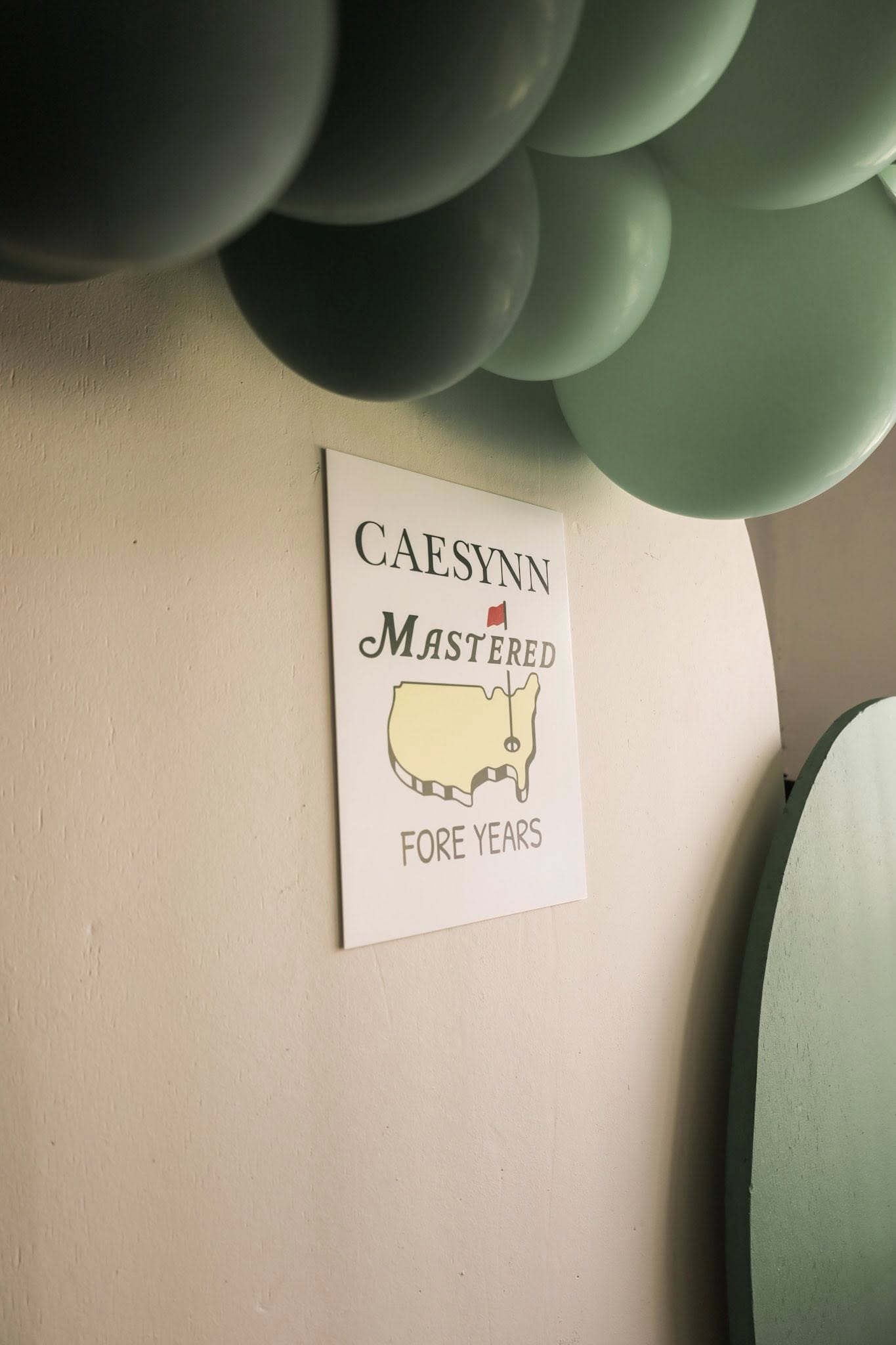 Golf themed birthday sign reading Caesynn Mastered Fore Years with balloons