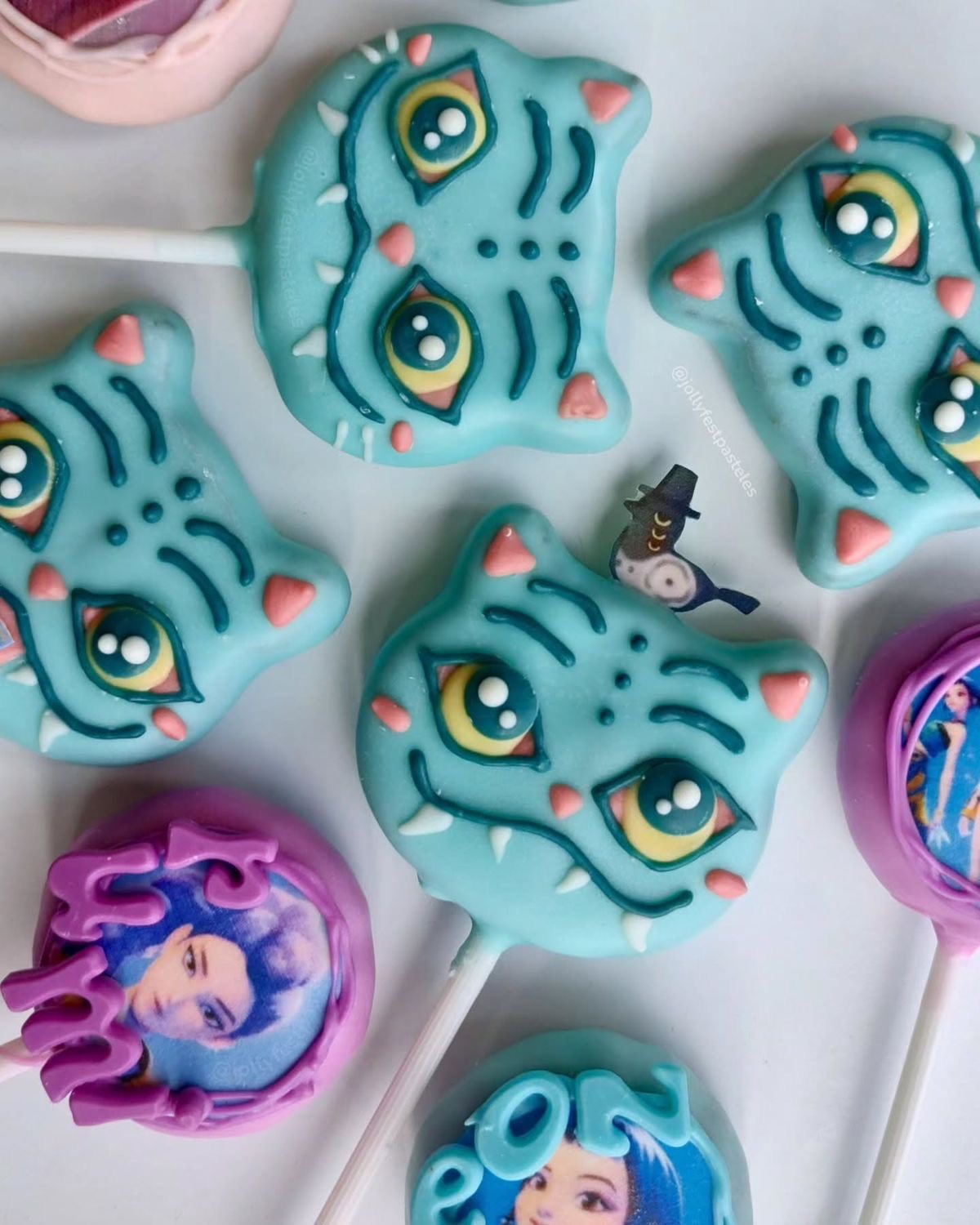 Assorted custom cake pops decorated with blue cat faces and character portraits