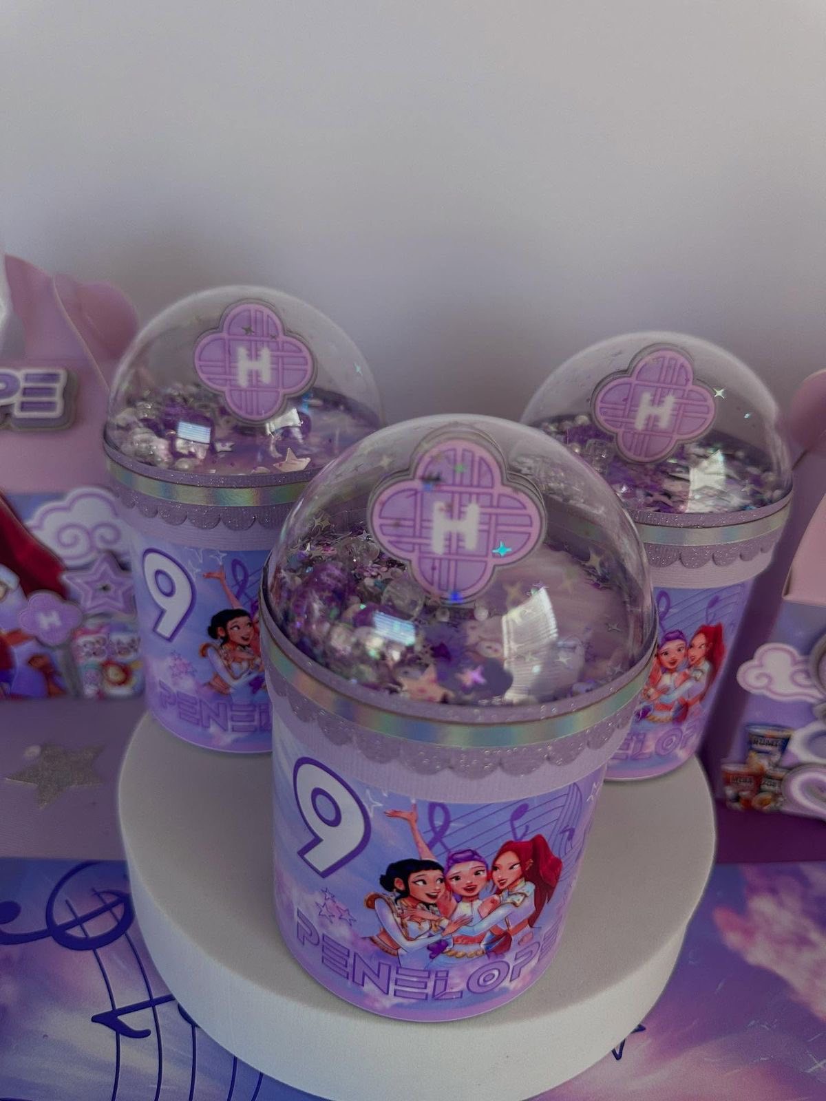 Set of custom purple personalized party favor shakers with character illustrations and number nine for a birthday.